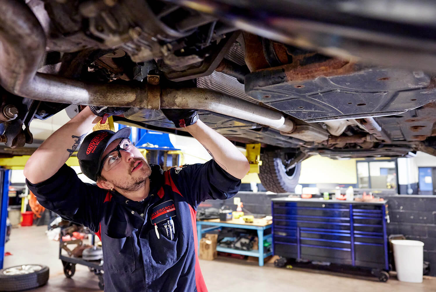 Auto technician student looking under a car.