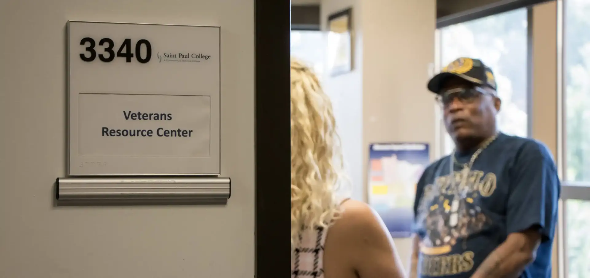 photo of students chatting in veterans center with sign on door reading 3340 Veterans Resource Center