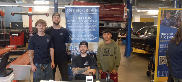 Students in the automotive lab in front of a banner for Inver Grove Honda