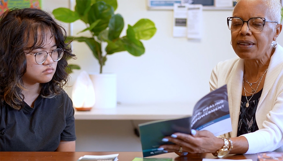 student listening to a counselor reading from a pamphlet